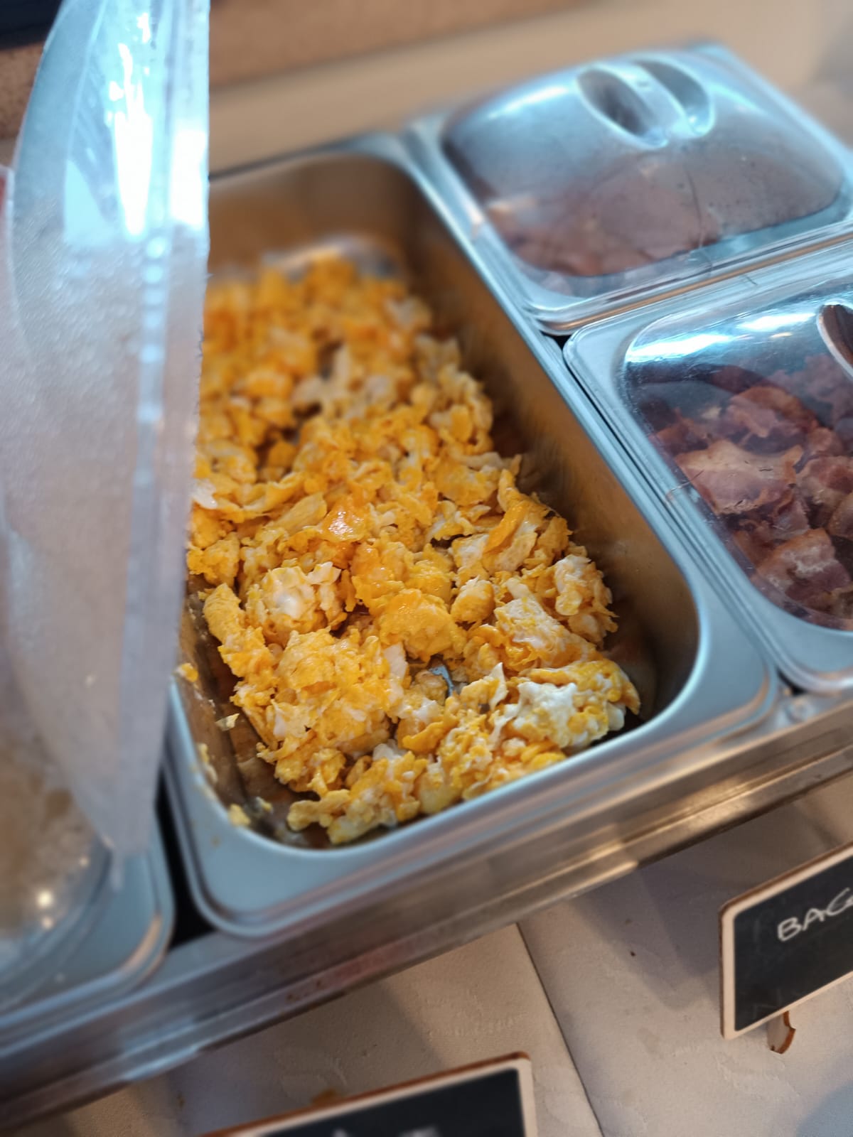 Uova strapazzate, bacon e prosciutto cotto al buffet caldo