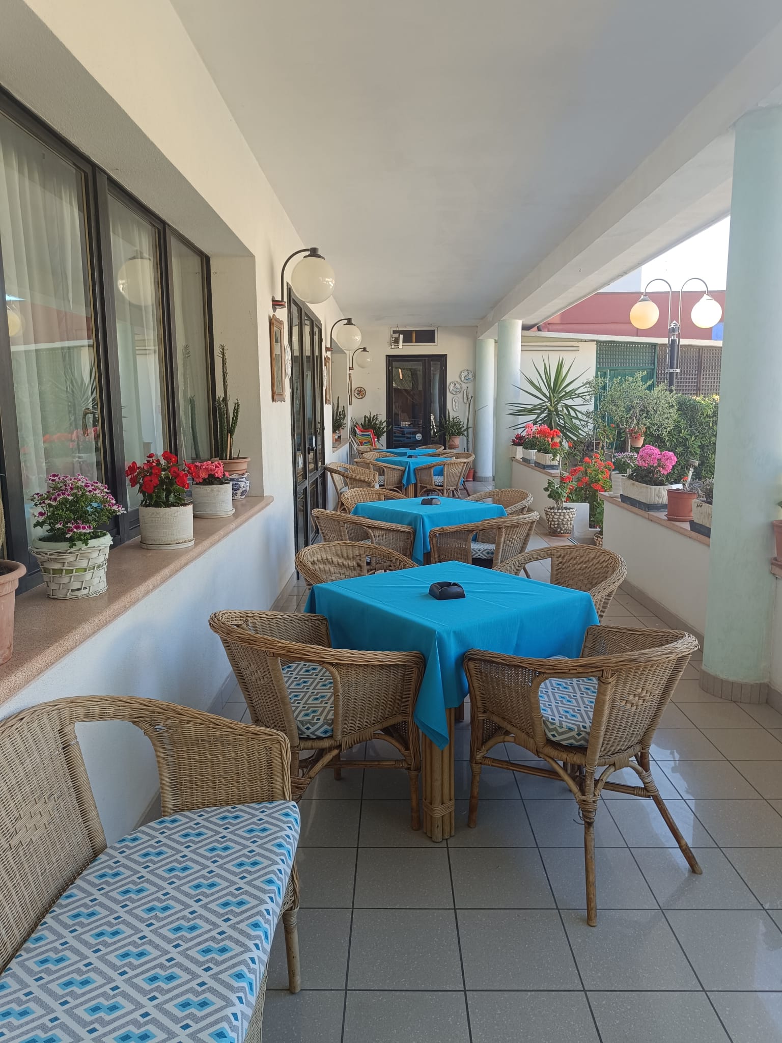 Veranda luminosa con poltroncine in vimini e tavoli fioriti